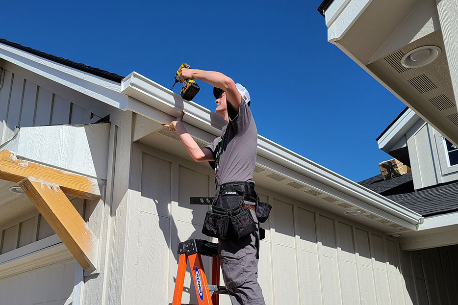 Installer fitting a seamless white gutter at the roof edge
