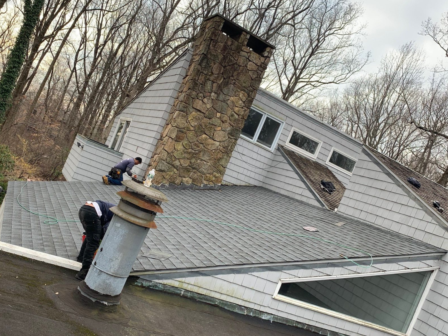 Roofers repairing shingles and roof details near a chimney