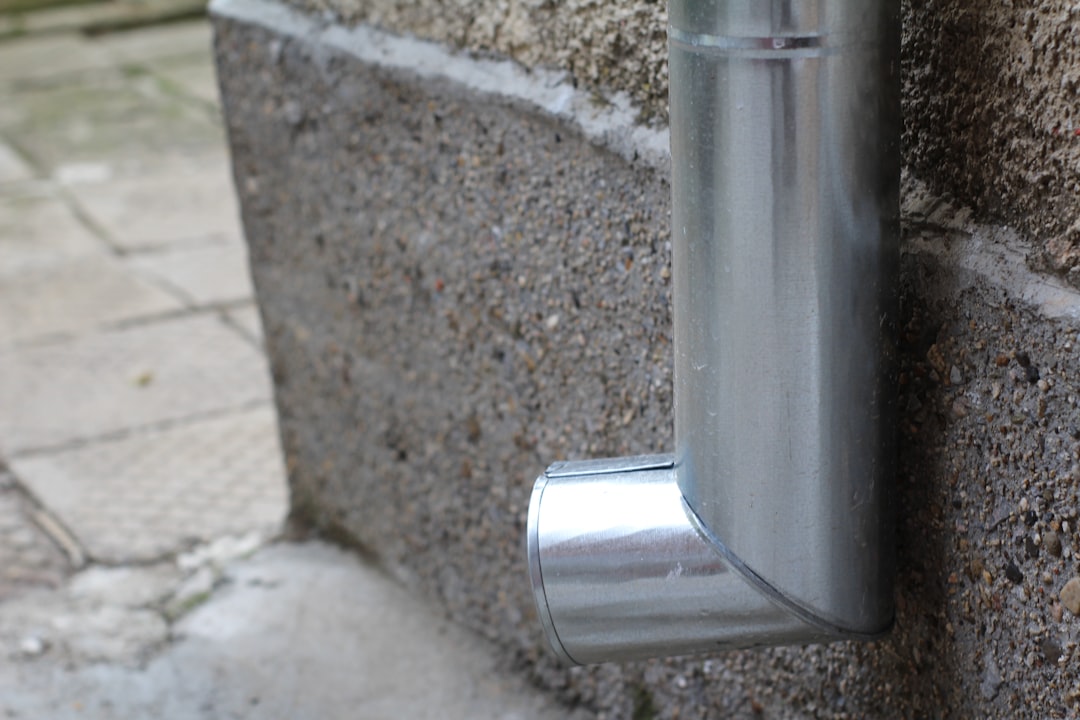 Metal downspout elbow directing rainwater away from a wall