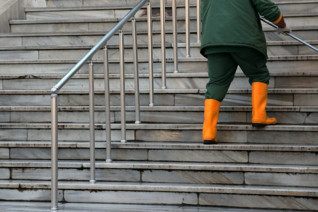 Worker cleaning outdoor stone steps with a washing wand