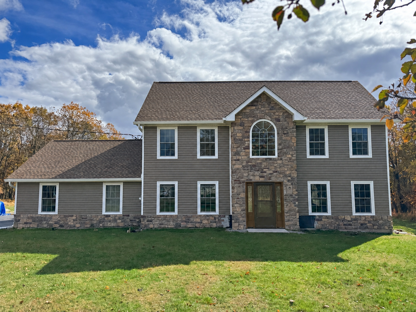 Two-story home with shingle roofing, gray siding, white trim and stone front